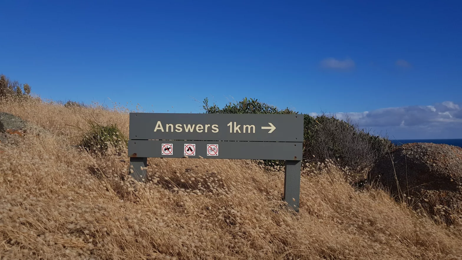 A sign on a hill that says Answers 1km with an arrow point to the right.