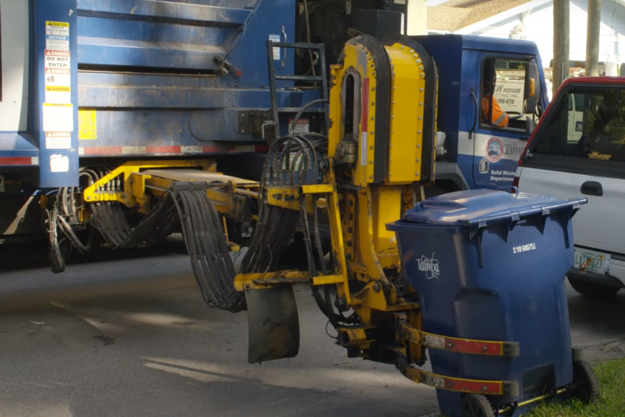 Garbage truck with mechanical arm picking up a can.